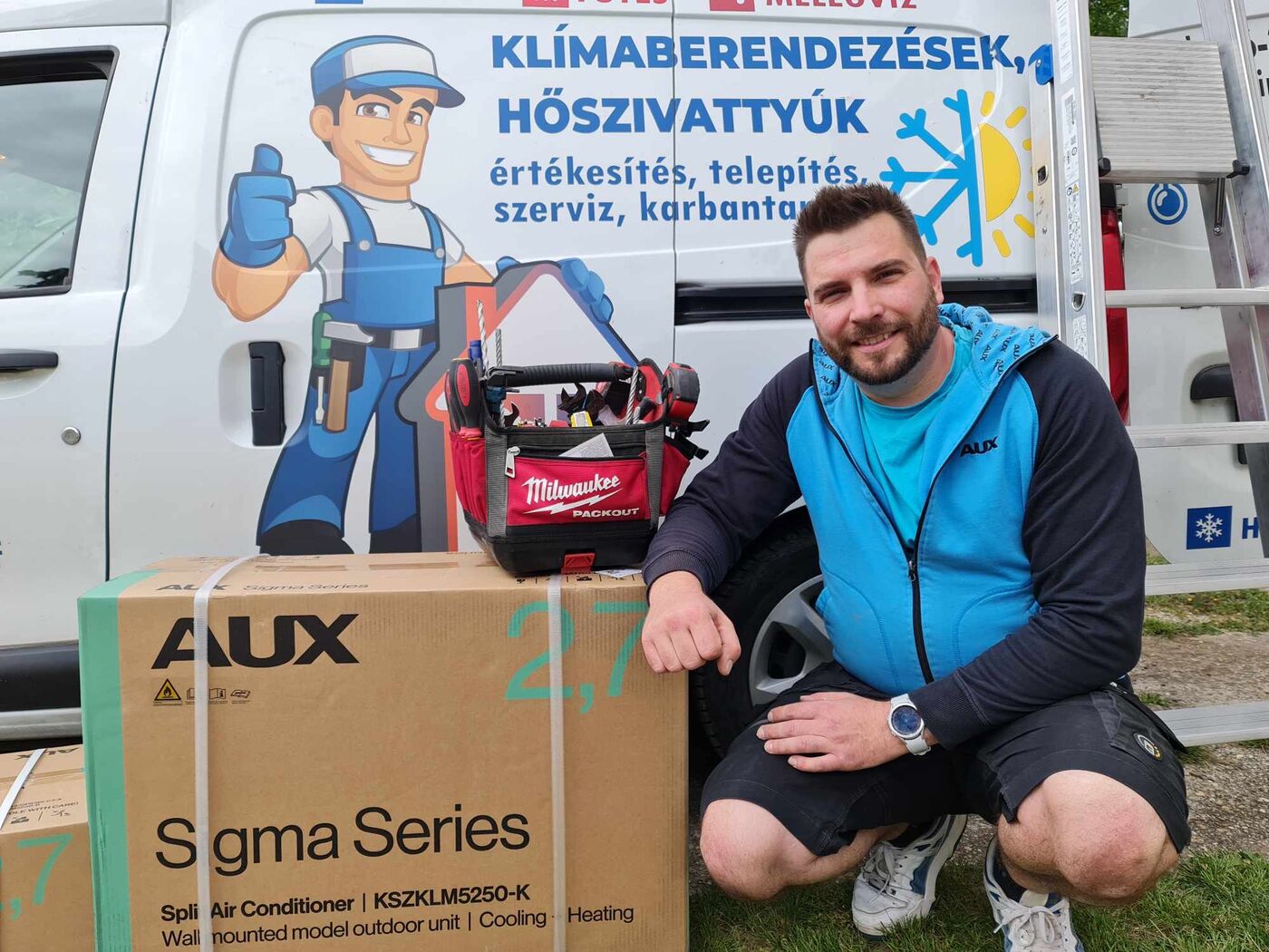 A Fanell szerelője egy AUX klímaberendezés dobozával a céges szerelőautó előtt